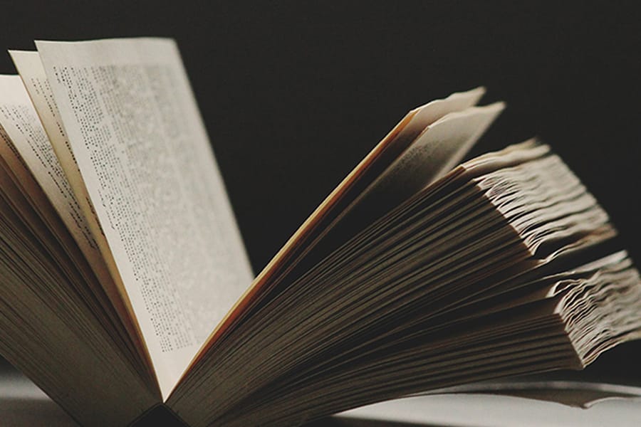 An open book with slightly worn pages fanned out, set against a dark background
