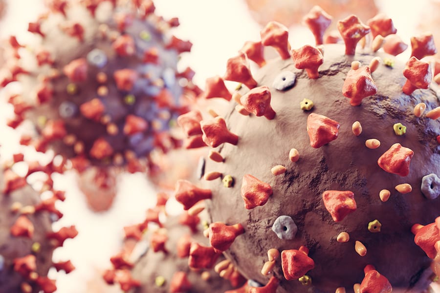 A close-up 3D illustration of the coronavirus (COVID-19) showing its spherical surface covered with red spike proteins.