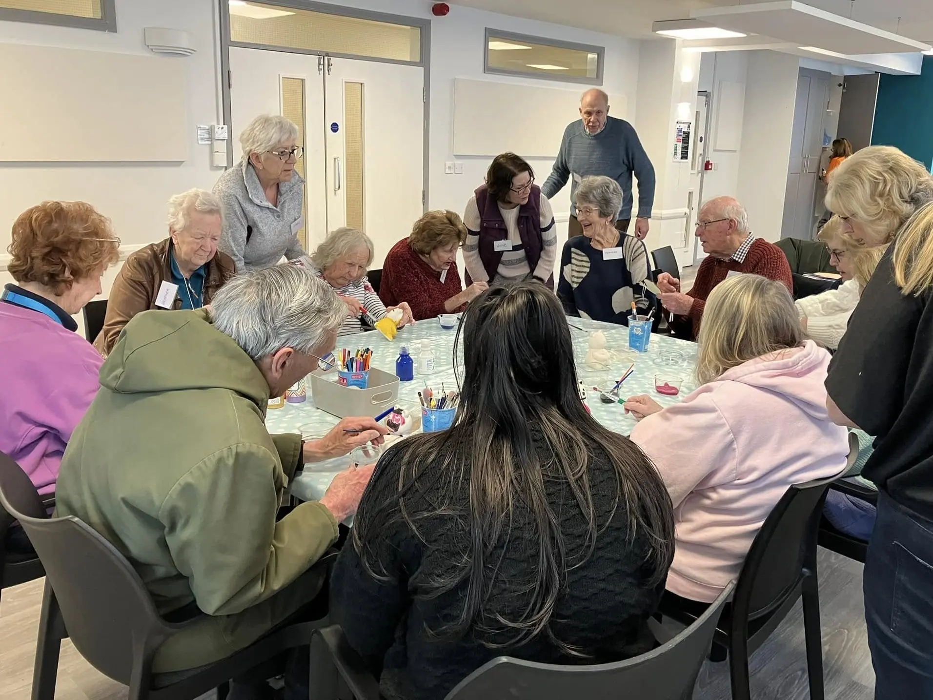 A group of older adults, supported by volunteers, take part in a creative arts and crafts session at the Memory Café.