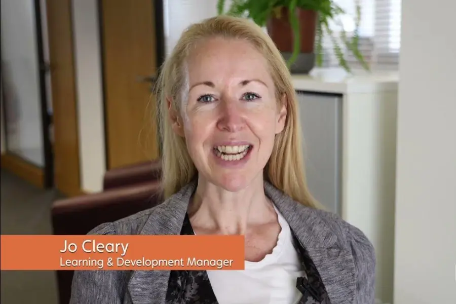 Jo Cleary, Learning & Development Manager at Unique Senior Care, smiling in an office setting with a nameplate overlay.