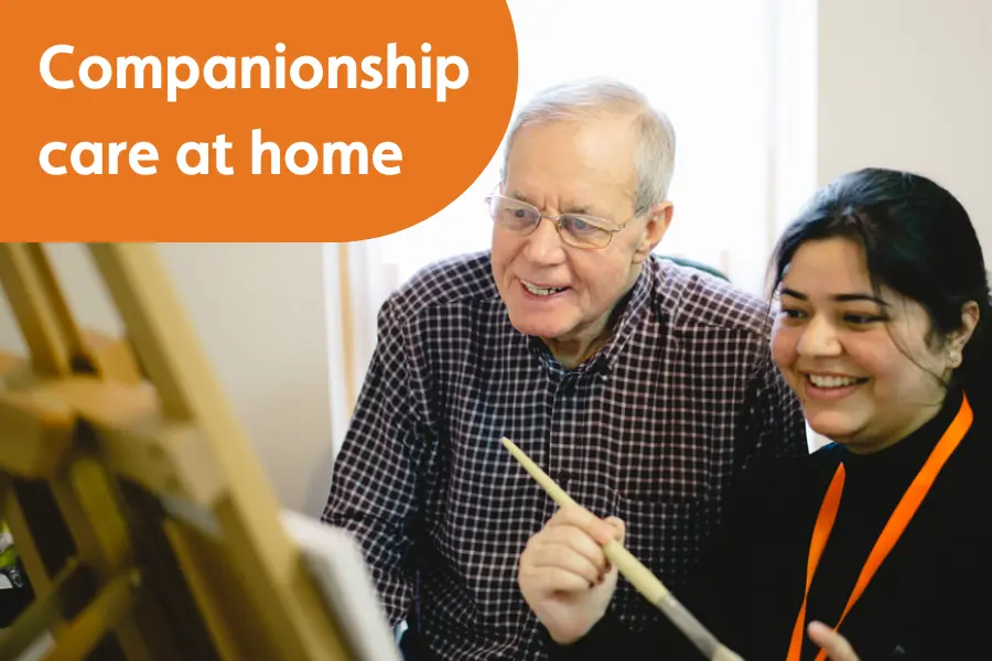 An elderly gentleman and his caregiver smiling while painting together, overlayed with the text 'companionship care at home'