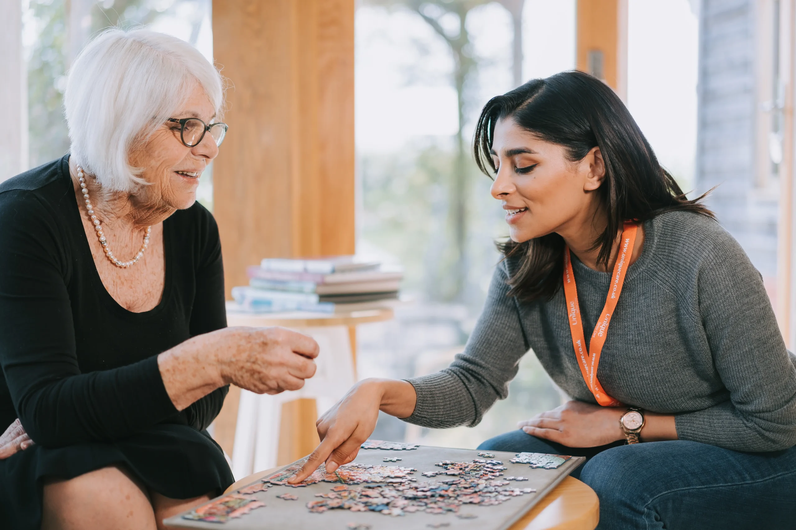 An elderly lady and her caregiver doing a jigsaw puzzle together