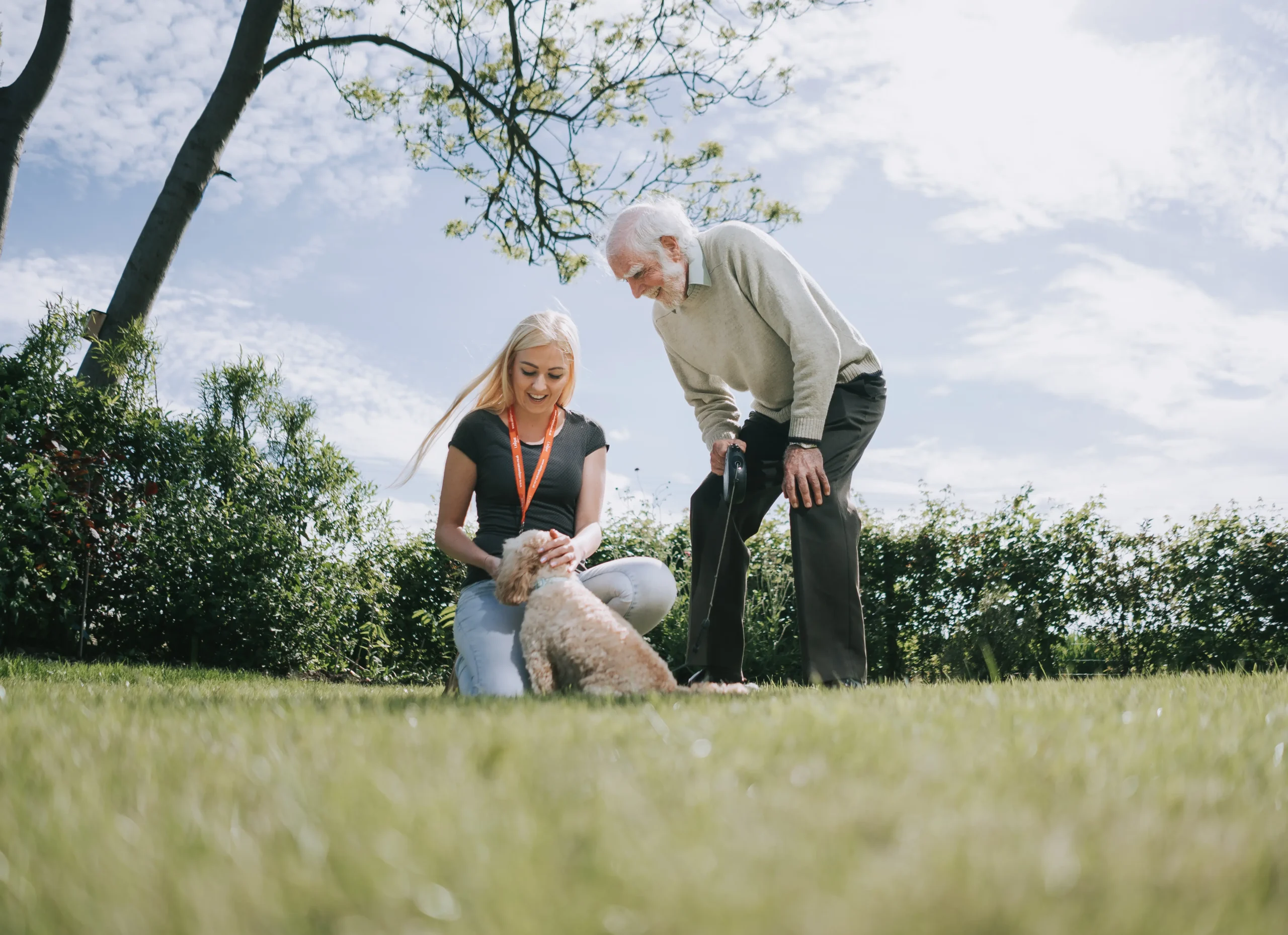 An elderly gentleman and his caregiver playing outside with his dog