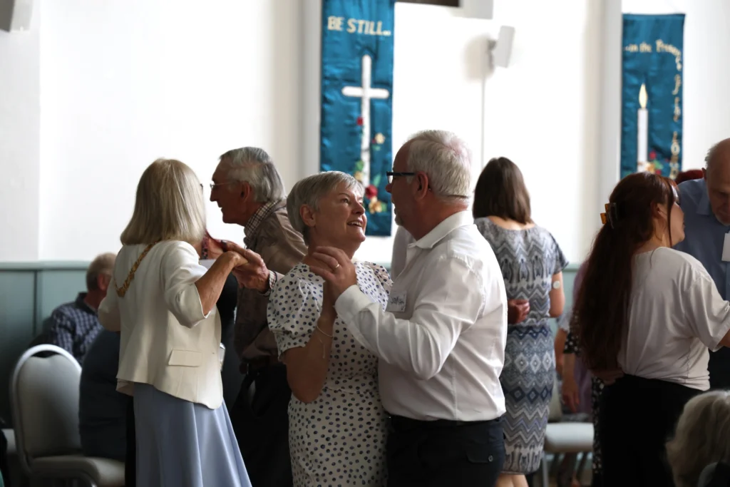 Couples dancing together and smiling at each other during the Memory Café Tea Dance.
