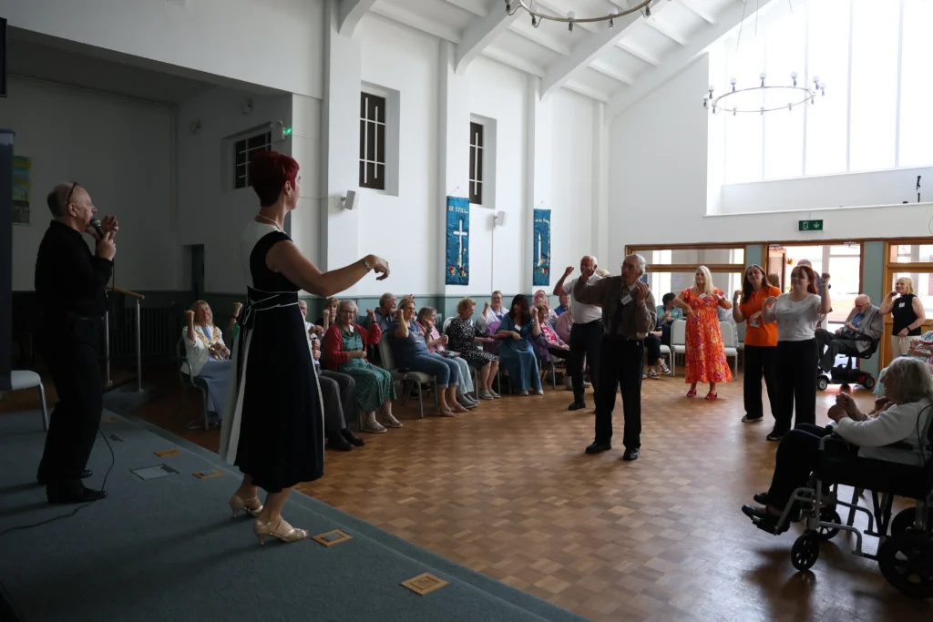 People dancing at the Memory Café event, with seated guests watching.