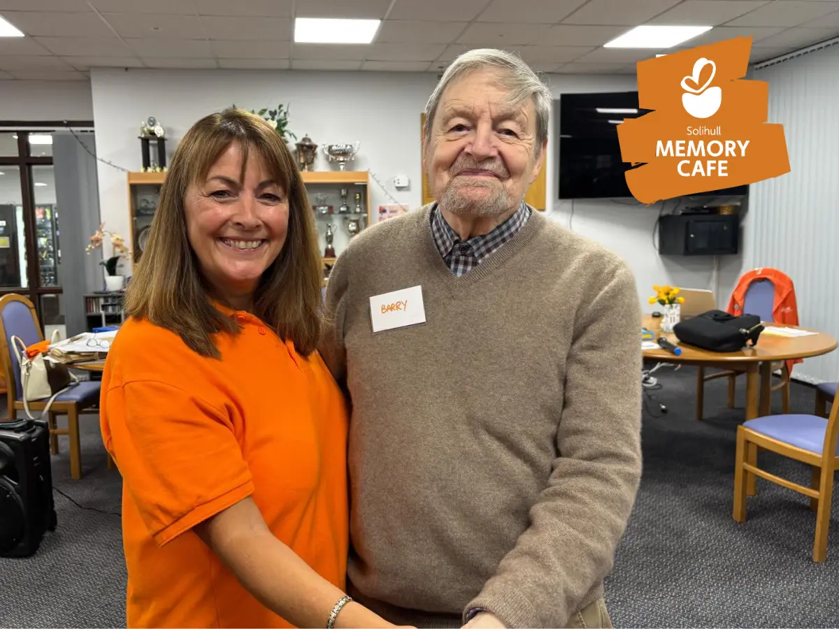 Coordinator Marian, with an attendee at the Solihull memory cafe, smiling at the camera