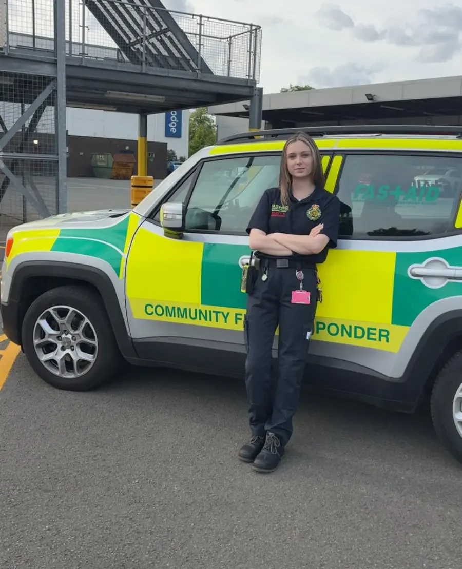Kara cAve, registered manager at Unique Senior Care, who is also a community first responder outside of work, stood outside of a community first responder vehicle, wearing her uniform.