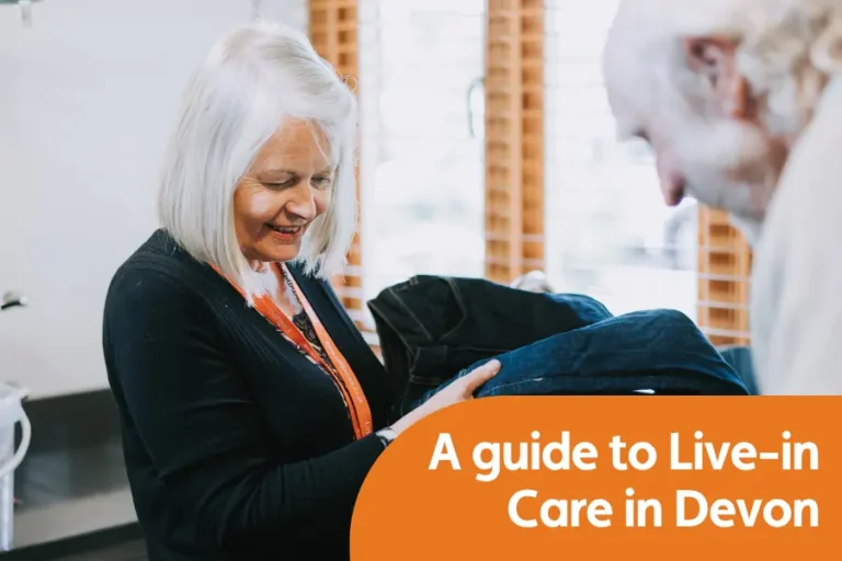 Featured image for blog comparing live-in care providers in Devon. Image shows a caregiver smiling while helping an elderly gentleman with his laundry
